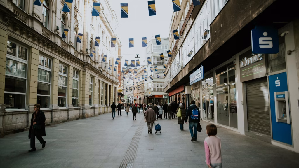 Pedestrian street in central Sarajevo with shoppers and Bosnian flags overhead