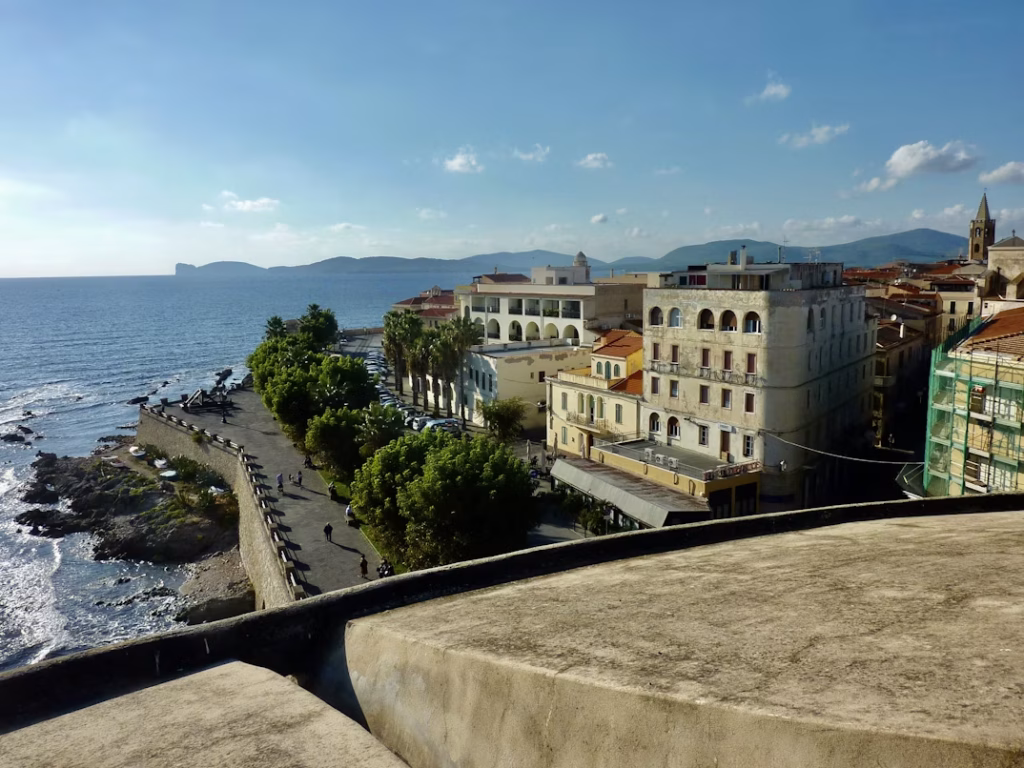 Seafront view of Alghero with historic buildings and coastal promenade
